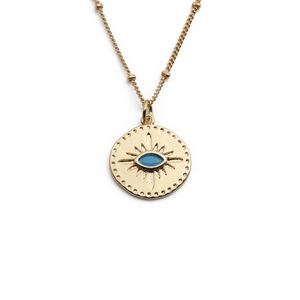 Macro detail of gold plated necklace with blue evil eye pendant on white background
