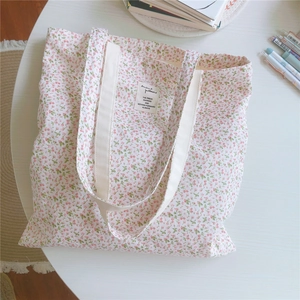 Detailansicht der Baumwolltasche mit Blumenmuster in Rosa und Grün auf weißem Tisch