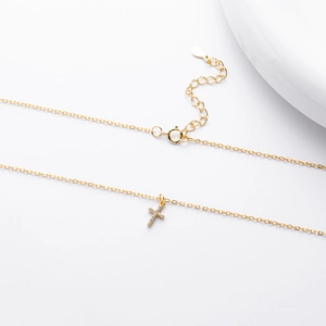 Macro detail of gold cross pendant with cubic zirconia and adjustable S925 sterling chain