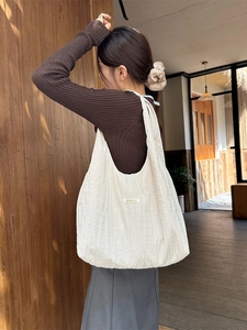 Minimalist large capacity pleated cloth tote bag in cream white color worn on shoulder