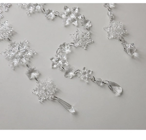 Macro view of clear acrylic snowflake ornaments with faceted teardrop crystal pendants