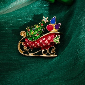 Detailed view of enamel Christmas sleigh brooch with festive gifts on green silk