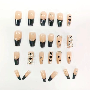 Détail d'ongles ballerine longs avec pointes French noires, motifs cœurs et nœuds argent
