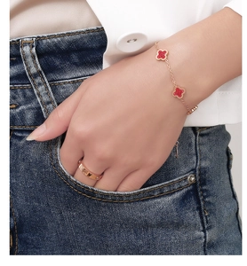 Close-up of golden clover bracelet and sparkling screw pattern ring on model hand