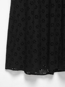 Detail of black cotton fabric with intricate hollow-out embroidery and floral patterns