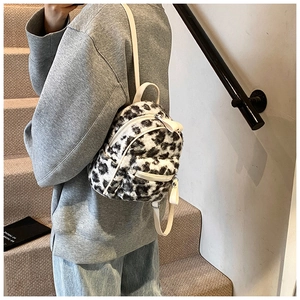 Détail d'un mini sac à dos en peluche noir et blanc avec bretelles en cuir blanc et zip argenté