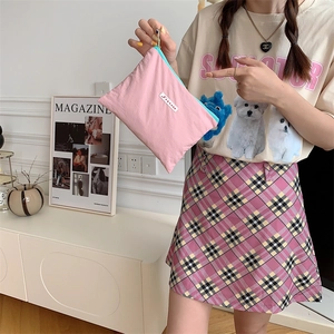Pink nylon macaron cosmetic bag with light blue zipper held in hand for detail