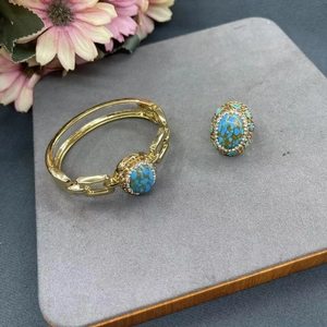 Set gioielli turchese dorato con bracciale e anello con gemma ovale su velluto grigio