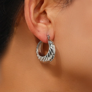 Silver stainless steel textured hoop earrings with diamond cut facets on female model