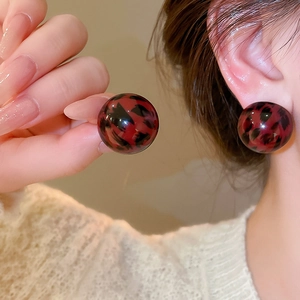 Macro detail of round resin leopard print stud earrings with a glossy vintage finish
