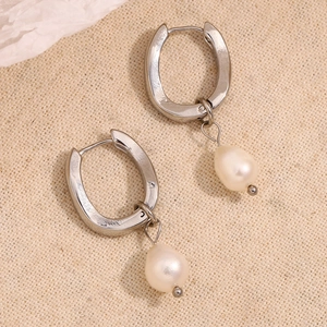 Macro detail of U-shaped silver hoop earring with elegant white teardrop pearl pendant