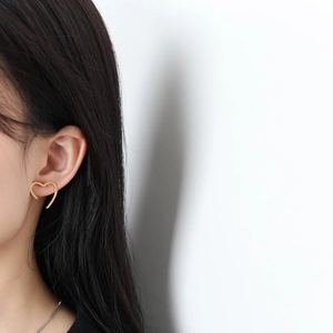 Elegant 18K gold-plated heart-shaped stud earrings worn by a model in a minimal setting