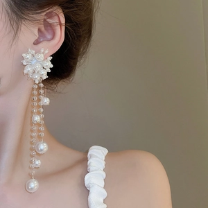 Close-up of elegant long pearl fringe earrings with floral cluster and silver needle studs