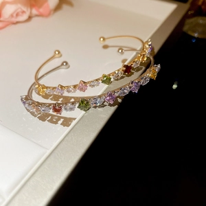 Close-up of gold and silver open bracelets with colorful star-shaped cubic zirconia