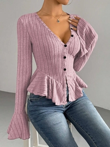 Close-up of pink knit top with ruffled hem, trumpet sleeves, and black buttons detail