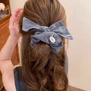 Macro shot of a dark grey pleated bow hair scrunchie with white bohemian floral patterns