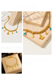 Detail of gold butterfly and blue evil eye charms on a beaded titanium steel chain
