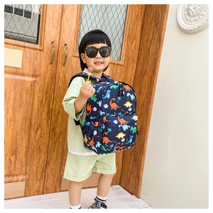 Detailed view of child wearing a dark blue dinosaur backpack against a wooden door background