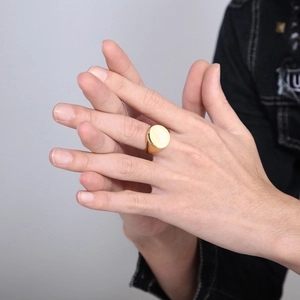 Minimalist gold oval signet ring for men in polished stainless steel on model's hand