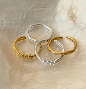 Macro shot of twisted rope and knotted 925 sterling silver rings in gold and silver tones