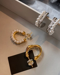 Detailed view of silver and gold pearl earrings with rhinestones on soft paper