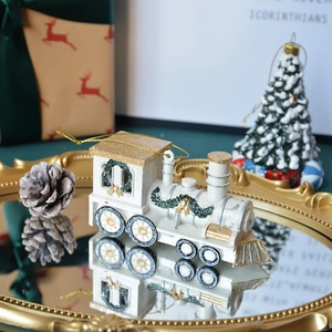 White and gold resin Christmas train ornament with a green wreath and gold hanging string