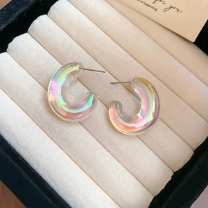 Macro view of iridescent C-shaped acrylic earrings in a beige velvet jewelry box