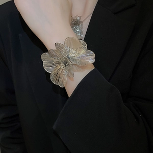 Detailed view of an oversized hollow floral cuff bracelet with intricate silver metallic weave