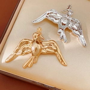 Detailed view of polished gold and silver bird brooches showing front and back pin structure