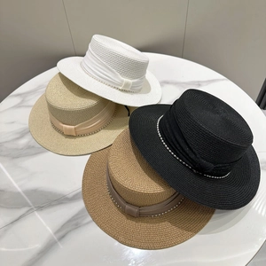 Detail of four flat-top straw hats with satin ribbons and elegant pearl chain accents