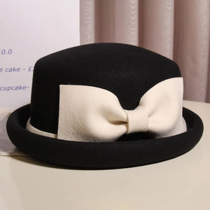 Elegant black wool cloche hat with a large cream bow and stylish curled rim