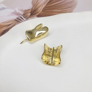 Abstract fluid teardrop gold stud earrings with mirror finish on a white ceramic tray