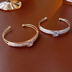 Detailed view of open flower bracelets in gold and silver with zircon settings