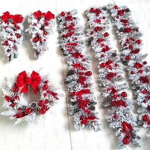 Detail of flocked Christmas wreaths and teardrop swags with red bows and pinecones