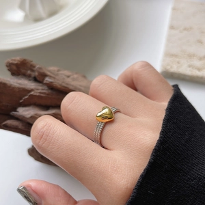 Detail of s925 silver beaded chain ring featuring a polished gold heart on model's finger