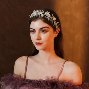 Detail of silver bridal floral headband with crystals worn by a model in soft lighting
