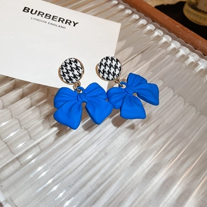 Detailed close-up of blue bow earrings with houndstooth pattern fabric on a glass tray
