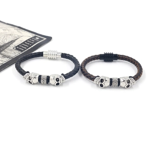 Close-up of woven leather bracelets in black and brown with skull and magnetic clasps