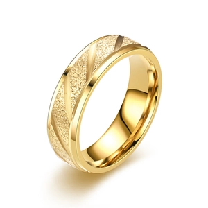 Primo piano di anello in acciaio al titanio dorato con trama smerigliata e strisce diagonali