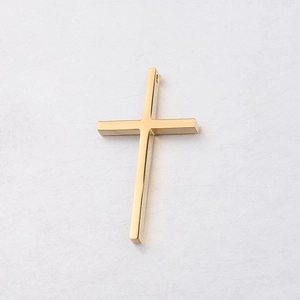 Macro shot of mirror-polished gold cross pendant with pre-drilled hole for DIY jewelry