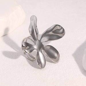 Detailed view of an irregular petal shaped silver ring on a white marble stone base