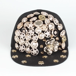 Close-up of black hip hop hat featuring metal studs, rivets, and lion head medallions