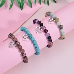 Détail de bracelets en pierres naturelles avec pendentifs en cœur gravés Mom