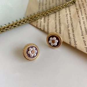 French vintage gold flower earrings with pearls and red enamel on classic newspapers
