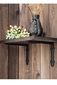 Close-up of vintage black cast iron bracket supporting a rustic solid wood shelf