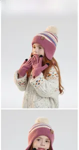 Detail of pink knitted winter hat with plush pom-pom and matching gloves for children