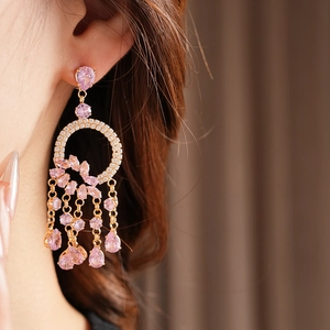 Detailed close-up of pink zircon droplet tassel earrings worn by a model in soft lighting