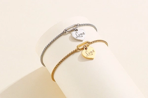 Detail of gold and silver heart bracelets with Love engraving on stylish box chains