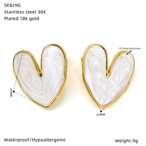 Detail view of heart-shaped white oil-dripping earrings with gold-plated edges and size data