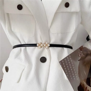 Close-up of thin black leather belt with pearl buckle on white ribbed blazer jacket